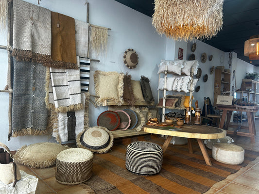 Espace cosy avec tapis en fibre naturelle, poufs tressés et coussins colorés dans la boutique OQENA