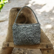 Sac à main en raphia bleu texturé posé sur un support en bois rustique en extérieur