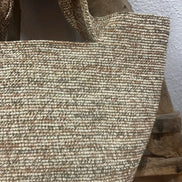Sac en raphia naturel tressé avec texture fine, posé sur un tabouret en bois rustique