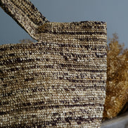 Sac en paille tressée naturelle avec fond gris et décor de plantes séchées