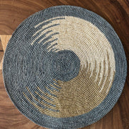 Set de table rond en raphia bleu et naturel posé sur une surface en bois brun