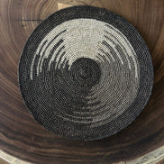 Set de table rond en raphia taupe et noir sur table en bois avec motif naturel