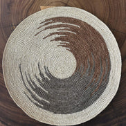 Set de table en raphia naturel beige, marron et gris, posé sur une table en bois foncé