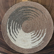 Set de table rond en raphia marron et beige tressé posé sur table en bois naturel